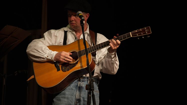 Man on stage with acoustic guitar